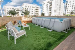 a pool with chairs and a tub on a lawn with buildings at Sunset - Achziv Beach Apartment - סנסט חוף אכזיב in Nahariyya