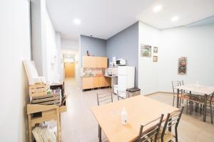 a room with tables and chairs and a kitchen at Albergue Barullo in Sarria
