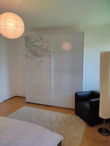 a bedroom with a large white cabinet and a black chair at La Vista - Apartment mit Traumblick & Garten in Marlengo