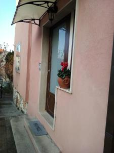 Appartamento Turistico "ortensia" في أنكونا: مبنى وردي مع نافذة مع نبات الفخار