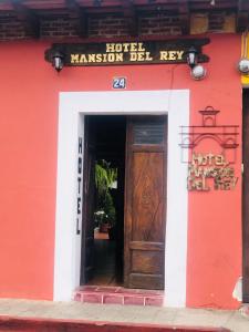 a red building with a wooden door and a sign at Hotel Mansion Del Rey in Antigua Guatemala