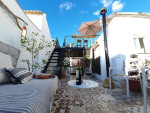 a patio with a bed and a table with a bottle of wine at Casa Maroma in Cómpeta