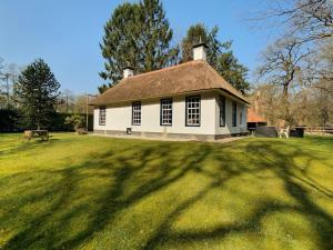 een klein wit huis met een groot grasveld bij Midden in de Friese bossen op landgoed Princenhof in Oranjewoud