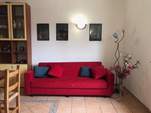 un divano rosso in un soggiorno con foto appese al muro di La Casa di Demetra. Un Paradiso tra gli Olivi. a Montecchio