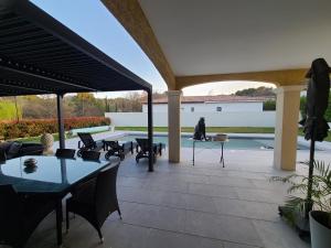 a patio with tables and chairs and a pool at Villa Provençal in La Roque-dʼAnthéron