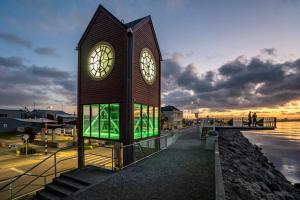 un bâtiment avec une tour d'horloge à côté de l'eau dans l'établissement Copthorne Hotel Greymouth, à Greymouth