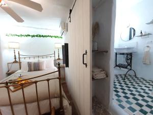 a bedroom with a bed and a bathroom with a sink at Casa Maroma in Cómpeta
