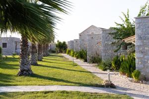 a row of palm trees next to a stone wall at Aktaion Resort in Gythio