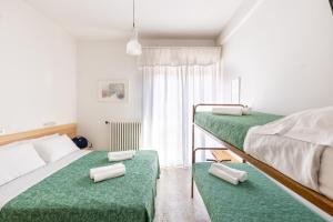 een slaapkamer met 2 stapelbedden met groene lakens bij Hotel Morena Riccione Centrale in Riccione