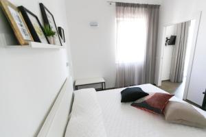 1 dormitorio con 1 cama blanca y 2 almohadas en Via Del Faro Apartments, en Torre Canne