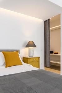 1 dormitorio con 1 cama con almohada amarilla y lámpara en Blueisla GREY Studio Town Mykonos, en Mykonos ciudad