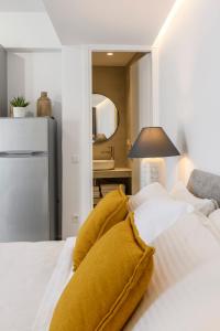 1 dormitorio con cama blanca y almohadas amarillas en Blueisla GREY Studio Town Mykonos, en Mykonos ciudad