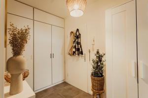 a hallway with white cabinets and a vase with plants at Stilvolles Apartment in ruhiger Lage in Leipzig