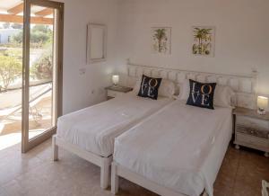 una camera da letto con un grande letto bianco con due cuscini di Viviendas Ferrer - Formentera Break a Playa Migjorn