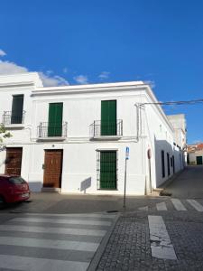 un edificio blanco con persianas verdes en una calle en La Sala by Casa de Rosita AT-BA-00215, en Fuente del Maestre