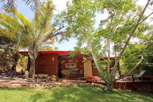 Cabaña de madera con techo rojo en un patio en Under the Walnut Tree Shade Lodge en Adi