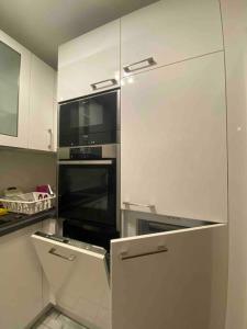 una cocina con horno negro y armarios blancos en Прекрасная квартира со всем необходимым для жизни en Duisburg