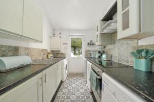 una cocina con armarios blancos y encimeras negras en Mulberry House - Detached 6 Bedroom House with Hot Tub & Private Parking en Canterbury