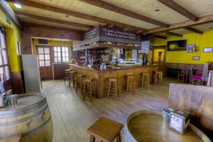 eine Bar in einem Restaurant mit Holztischen und -stühlen in der Unterkunft Hostal Rural La Tintoreria in Villablino
