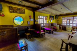 un restaurante con paredes amarillas, suelo de madera y mesas en Hostal Rural La Tintoreria, en Villablino