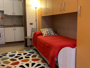 Cet appartement comprend une chambre avec un lit doté d'une couverture rouge et une cuisine. dans l'établissement Appartamento affitti brevi Verona Colors/G.B. Rossi friendly, à Vérone