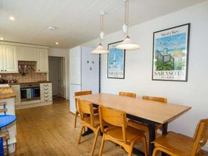 a kitchen and dining room with a wooden table and chairs at Sandy Bank in Rhosneigr