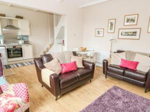 a living room with two leather chairs and a table at Cottongrass Cottage in Littleborough