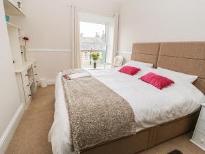 a bedroom with a large bed with two red pillows at Cottongrass Cottage in Littleborough