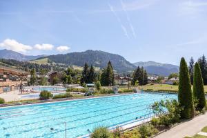 a large swimming pool with mountains in the background at Au Petit Flocon - Appartement 3 pièces, central et proche pistes - parking privé et wifi in Megève