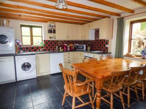 a kitchen with a wooden table and chairs and a kitchen with a washer at Blaendyffryn Fach in Llanybyther