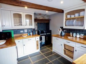 a kitchen with white cabinets and a stove at 2 Huxtables in North Molton