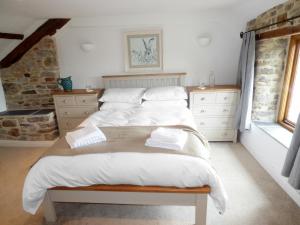 a bedroom with a large bed with white sheets at 2 Huxtables in North Molton