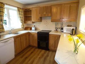 a kitchen with wooden cabinets and a black stove at Littlebeck in Rosthwaite