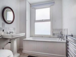 La salle de bains est pourvue d'une baignoire, d'un lavabo et d'une fenêtre. dans l'établissement Dutch Cottage, à Colchester