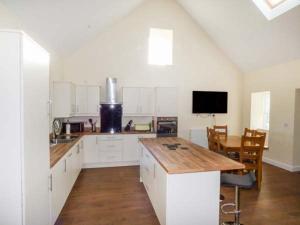 a kitchen with white cabinets and a wooden counter top at Ysgubor Newydd in Cemaes Bay