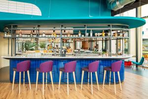 un bar con taburetes morados y rosados en YOTEL Amsterdam en Ámsterdam