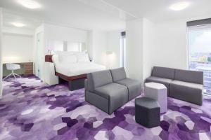 una camera d'albergo con letto, divano e sedia di YOTEL Amsterdam ad Amsterdam