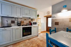 een keuken met witte kasten en een tafel met blauwe stoelen bij Cà Rosa in Mergozzo