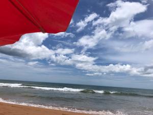 a red umbrella on the beach with the ocean at Casa beira mar Jacaraipe. in Serra
