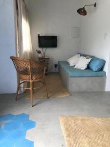 a room with a bed and a chair and a television at Pequeno Grande Paraíso in Arraial do Cabo