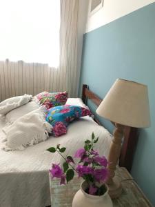 um quarto com uma cama e uma mesa com um candeeiro em Pequeno Grande Paraíso em Arraial do Cabo