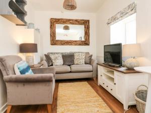 uma sala de estar com um sofá e uma televisão em Robin Cottage em Ilfracombe