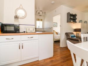 eine Küche mit weißen Schränken und einer Mikrowelle in der Unterkunft Robin Cottage in Ilfracombe + 5 Fotos