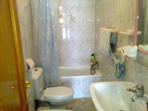 a bathroom with a toilet and a tub and a sink at Hostal Asensio Nijar in Níjar