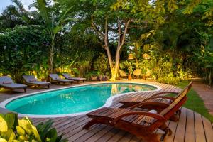 a swimming pool with a wooden deck and benches around it at Casa Das Águas Trancoso in Trancoso