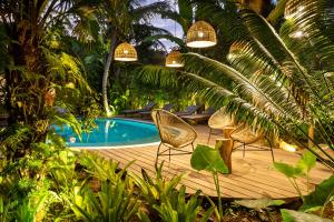 a wooden deck with two chairs and a swimming pool at Casa Das Águas Trancoso in Trancoso