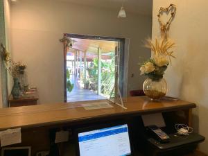 an office desk with a computer and a vase of flowers at Pousada do Grilo in Santo Antônio do Pinhal