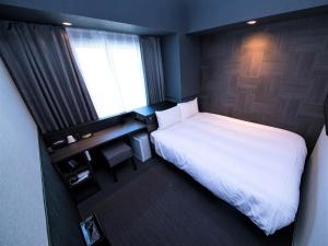 a small bedroom with a white bed and a window at CHISUN STANDARD Osaka Shin-Imamiya in Osaka