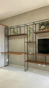a living room with shelves and a tv at Loft amplo, apenas 6km do Morro do Careca! (G) in Natal