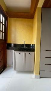 a kitchen with a sink and a yellow wall at Loft amplo, apenas 6km do Morro do Careca! (G) in Natal